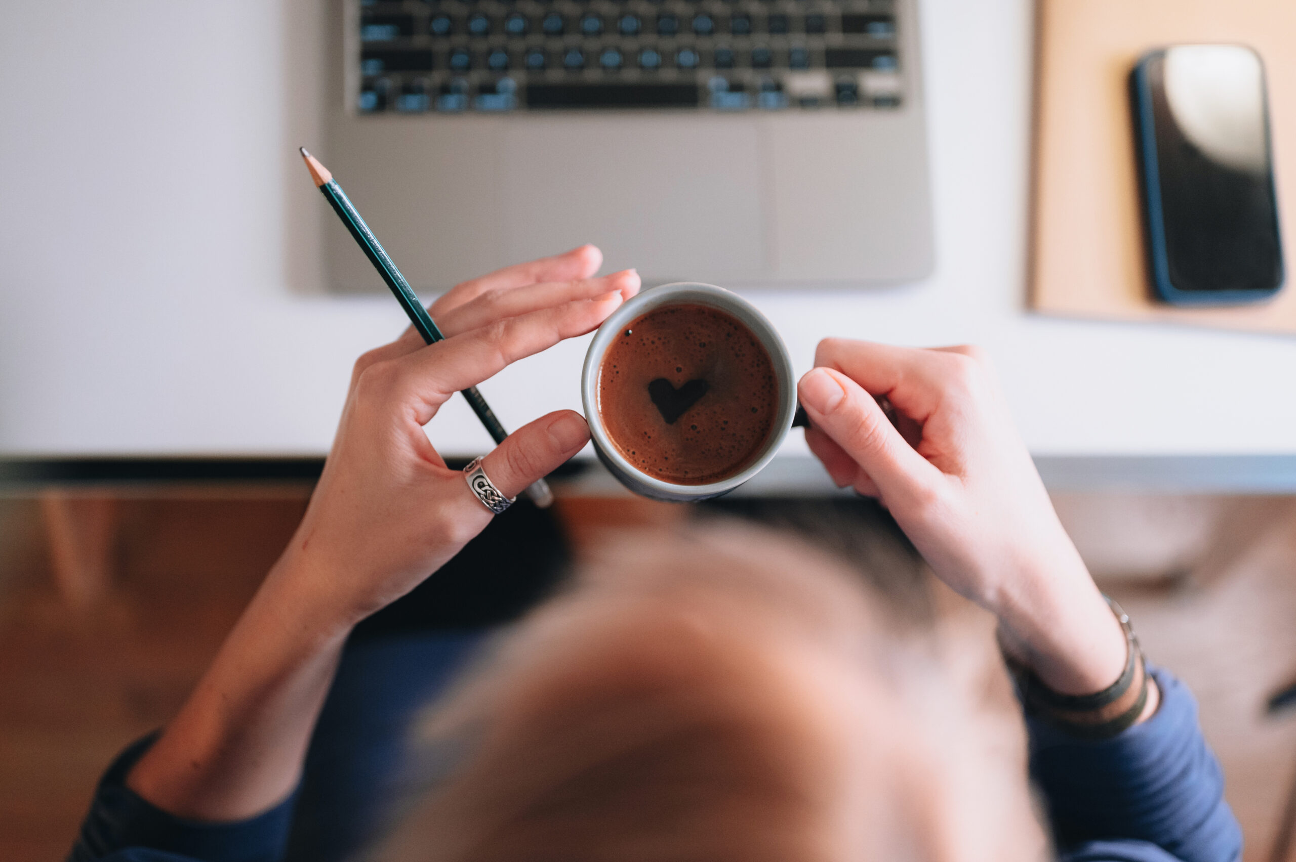 Directly above a young woman sitting at her desk and working on a computer in her bright home office.