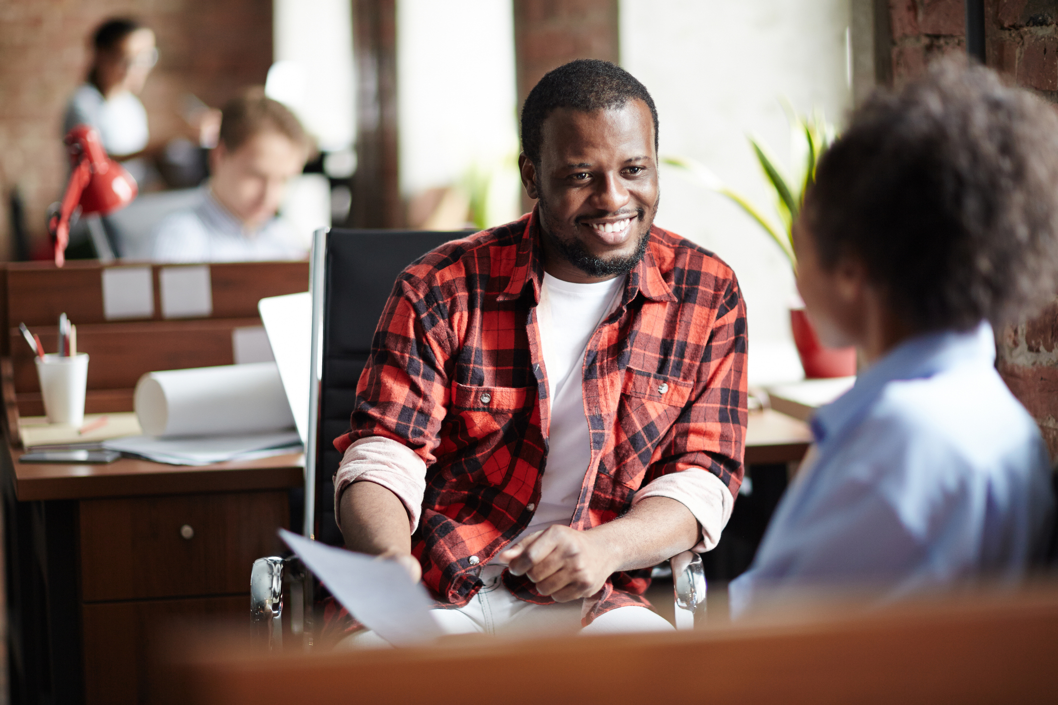 Smiling African businessman in casual clothes conducting the interview with woman at office